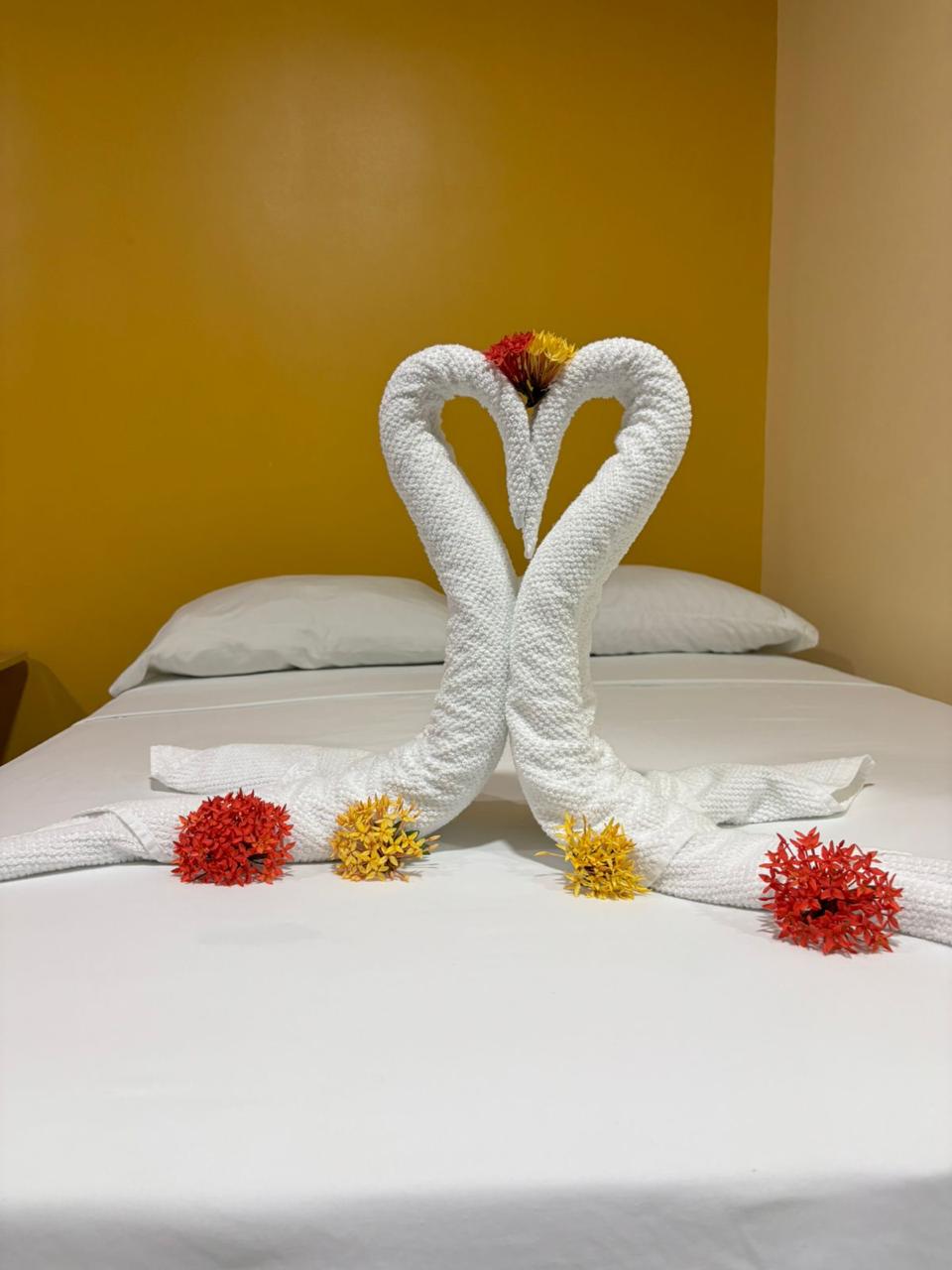 Detalle de toallas en forma de cisnes con flores sobre la cama
